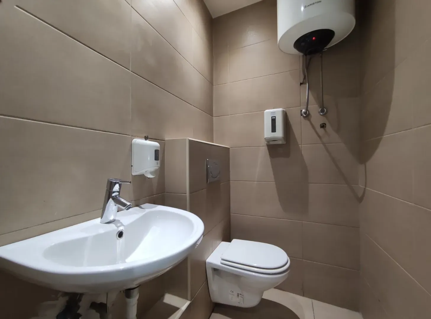 A small bathroom with a sink, toilet, and water heater.