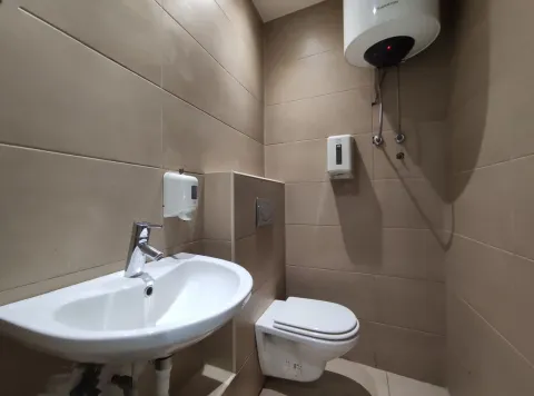 A small bathroom with a sink, toilet, and water heater. - image 5