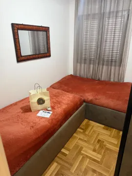 Manja spavaća soba sa dva kreveta, parketom na podu i ogledalom na zidu. - image 3