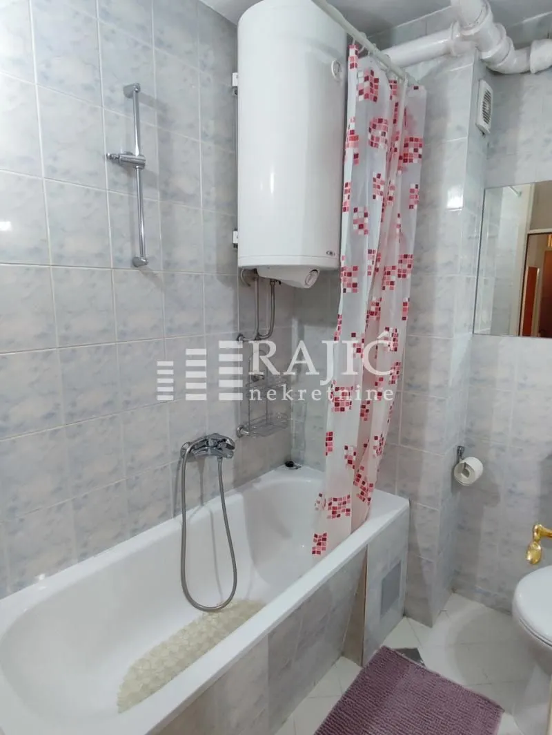 Small equipped bathroom with a bathtub and a water heater.