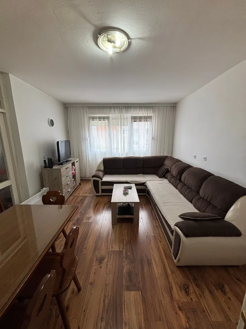 Dnevna soba sa garniturom, stočićem i trpezarijskim stolom.