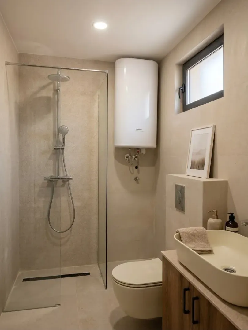 Modernly equipped bathroom with a walk-in shower, washbasin, and toilet in neutral tones.
