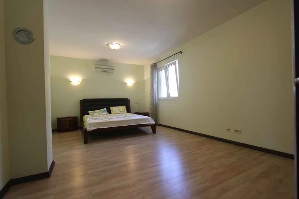 Svijetla spavaća soba sa bračnim krevetom i laminatom.