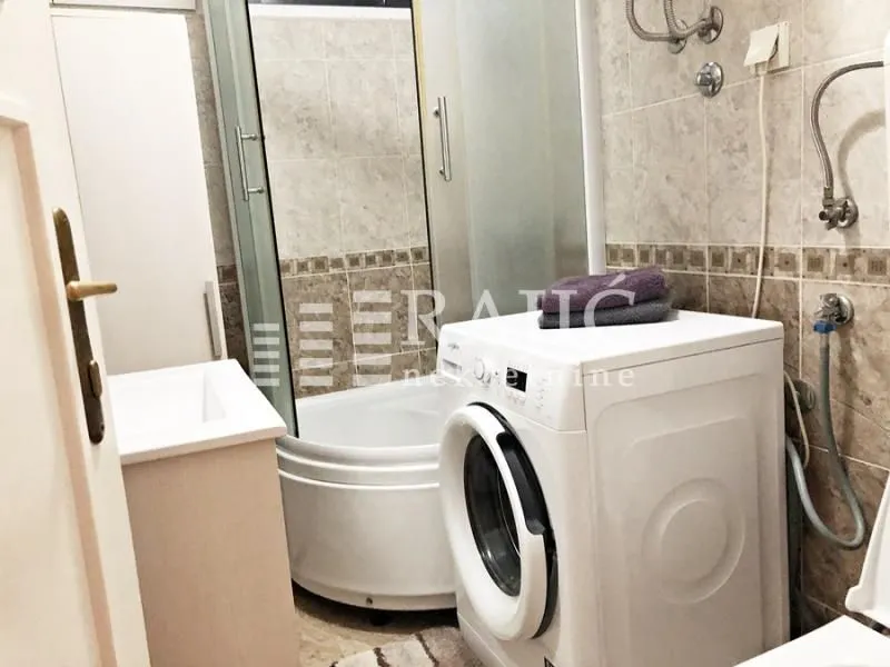 Smaller bathroom with a shower cabin and a washing machine.