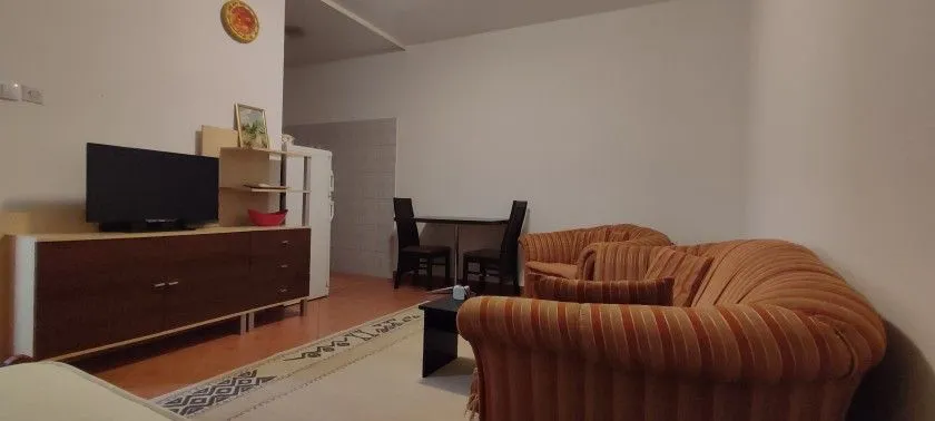 Dnevna soba sa garniturom, komodom i televizorom.