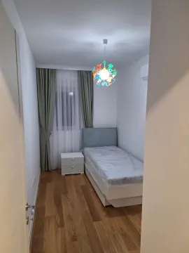 Mala spavaća soba sa jednim krevetom, noćnim ormarićem i šarenim lusterom. - image 12