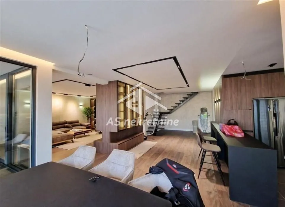 Spacious open-plan living room with dining area and stairs in a modern apartment.