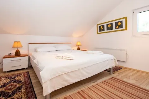 Spavaća soba sa bračnim krevetom, noćnim stočićima i kosim plafonom. - image 7