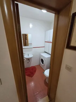 Small bathroom with a washing machine and red tiles, viewed through a doorway. - image 10