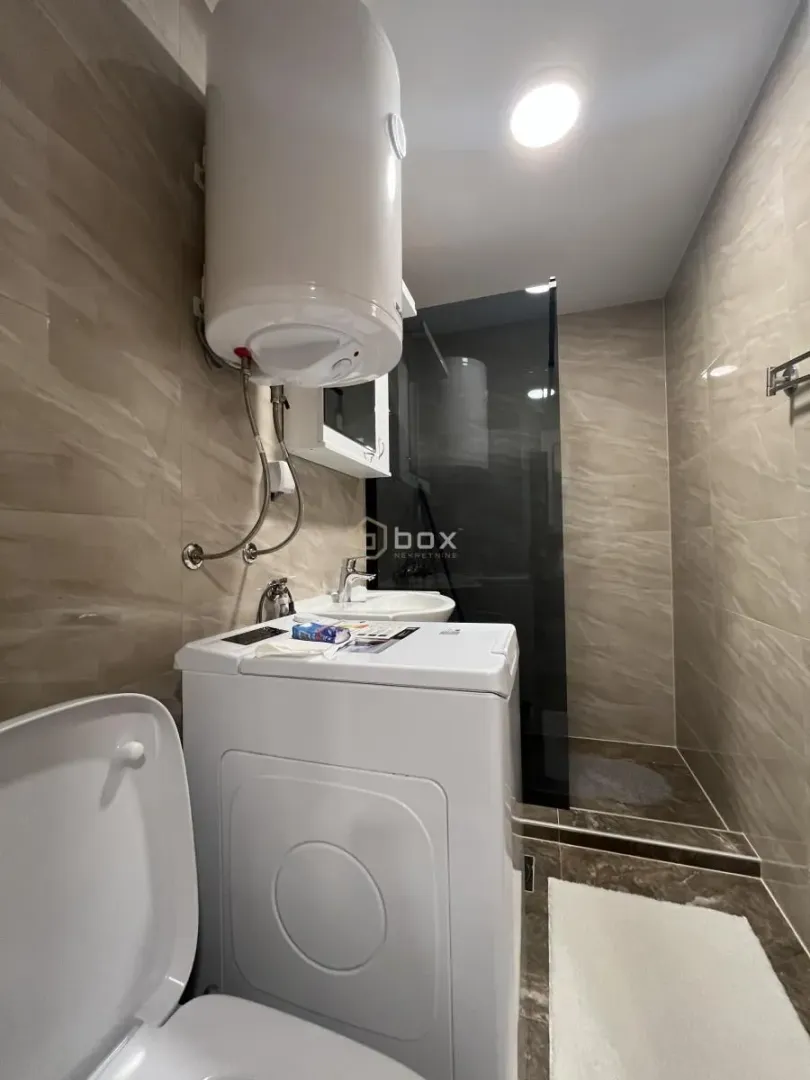 Kupatilo opremljeno sanitarijama, tuš kabinom i veš mašinom.