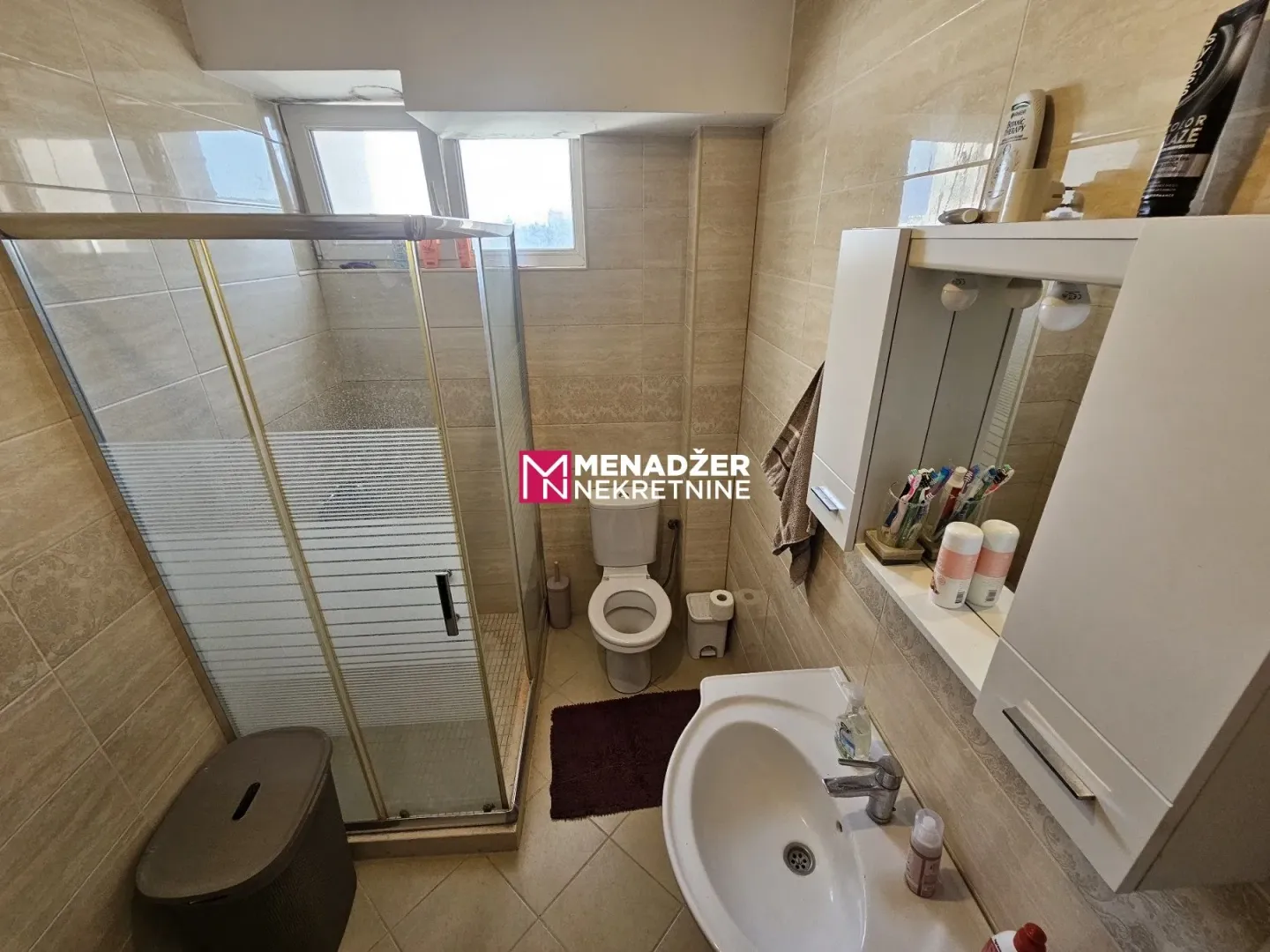 Small bathroom with a shower cabin, sink, and toilet.