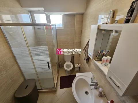 Small bathroom with a shower cabin, sink, and toilet. - image 5