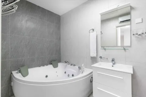 Modernly equipped bathroom with a corner hydro-massage bathtub and a vanity unit. - image 29