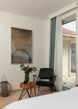 Ugao spavaće sobe sa udobnom foteljom, dekorativnim stočićem i izlazom na terasu. - image 14