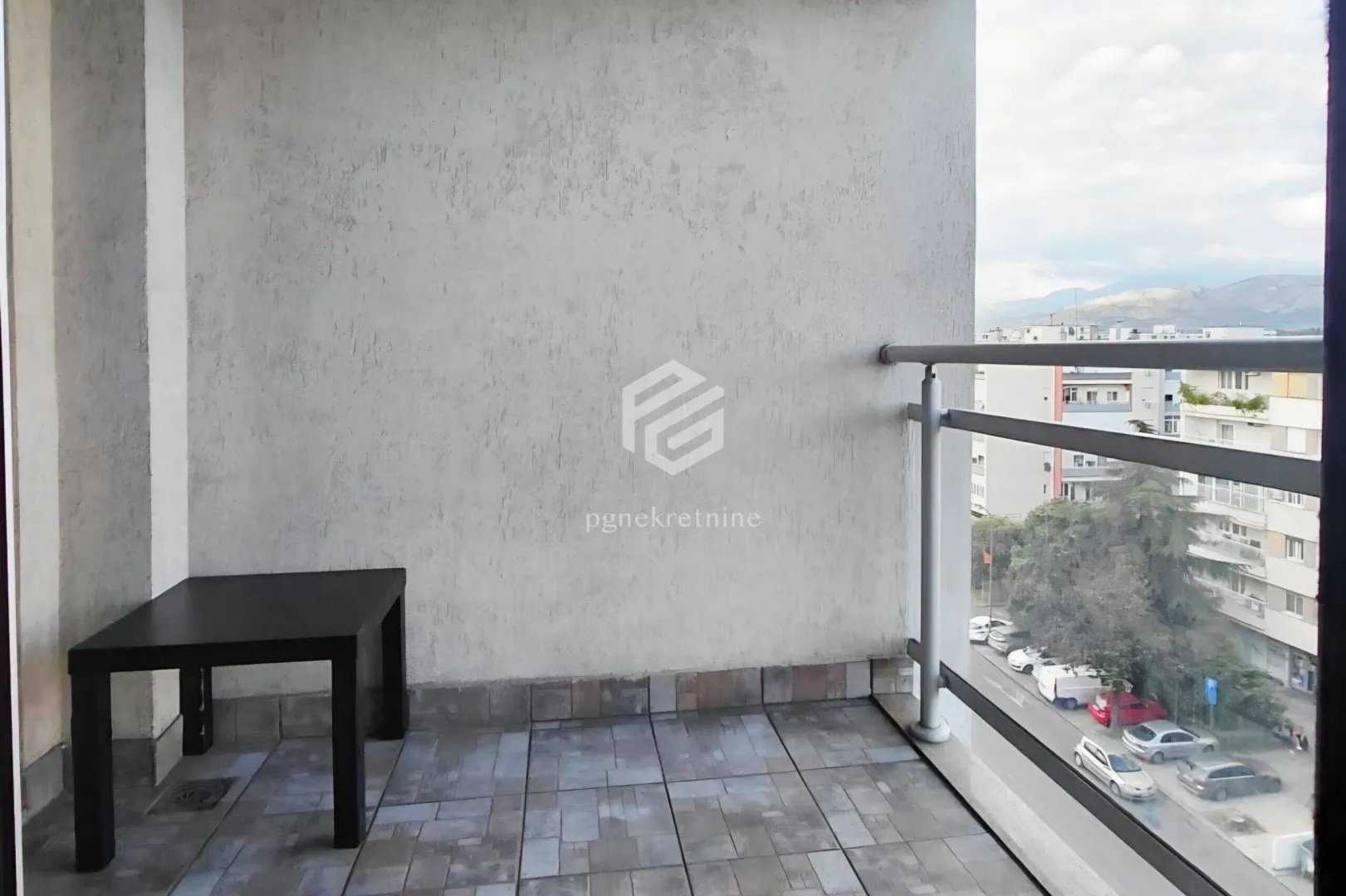 Natkriveni balkon sa popločanim podom i pogledom na gradsku ulicu.