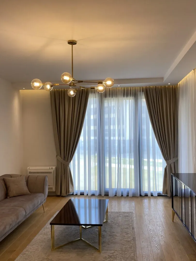 A bright living room with a modern chandelier and a large window.