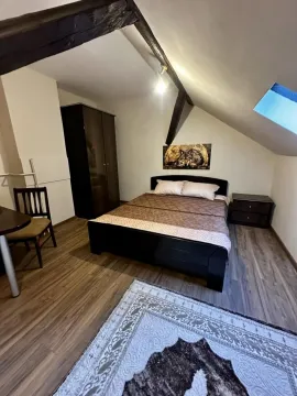 Potkrovna spavaća soba sa bračnim krevetom, ormanom i drvenim gredama. - image 3