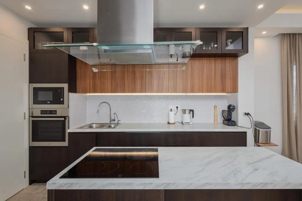 Modern kitchen with an island, built-in appliances, and a marble countertop.
