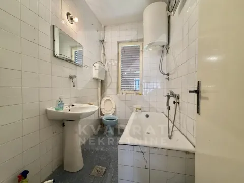 Manje kupatilo obloženo bijelim pločicama sa kadom, umivaonikom i wc šoljom. - image 25
