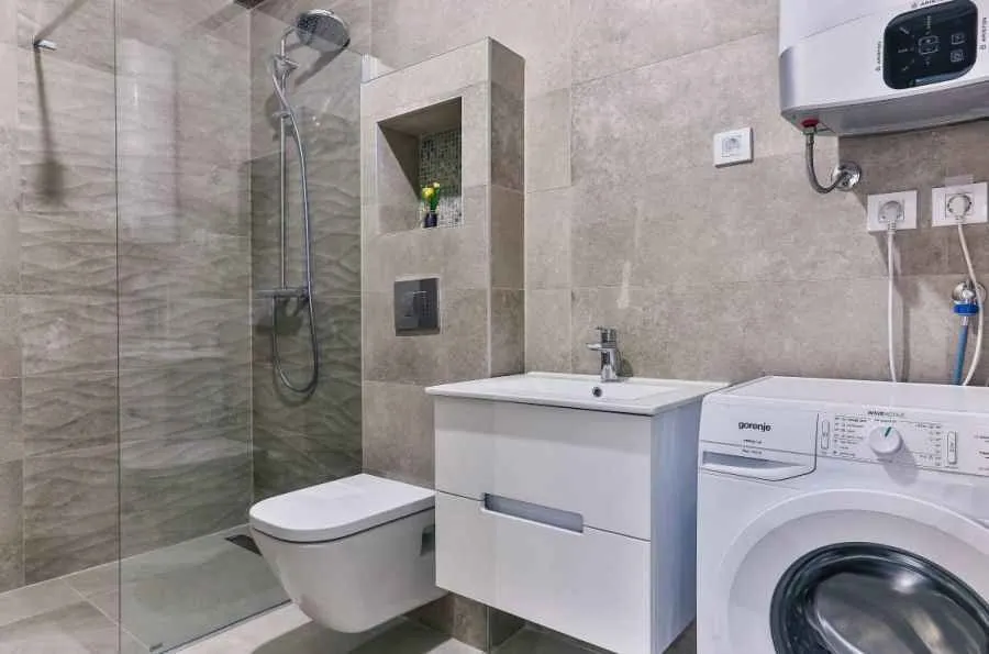 Moderno opremljeno kupatilo sa tuš kabinom, umivaonikom i veš mašinom.
