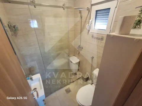 Kupatilo opremljeno tuš kabinom sa staklenim paravanom, umivaonikom i toaletom. - image 23