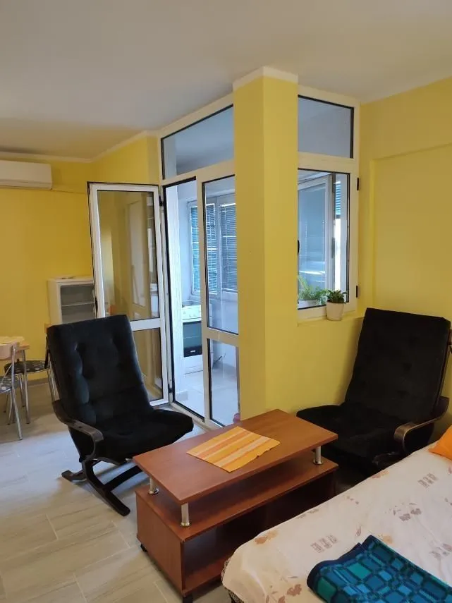 Living room with two black armchairs, a wooden table, and yellow walls.