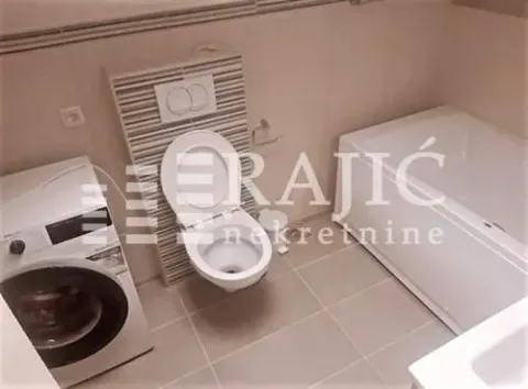 Small bathroom with sanitary facilities, bathtub, and washing machine. - image 11