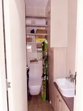 Smaller bathroom with a sink, toilet, and storage shelves. - image 13