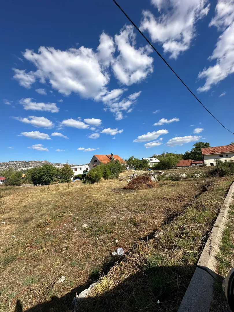 Pogled na plac i okolne kuće sa plavim nebom.