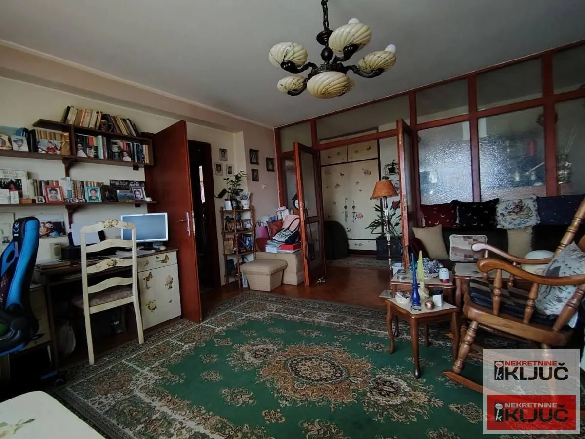 Dnevna soba sa radnim kutkom i policama za knjige.