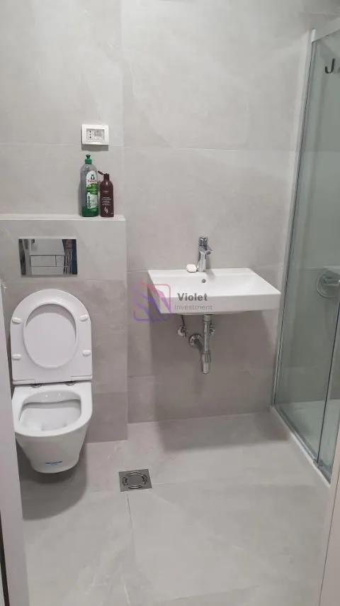Moderne kupatilo sa tuš kabinom, umivaonikom i toalet šoljom.