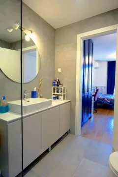 Modern bathroom with a washbasin and a mirror, overlooking a room through an open doorway. - image 2