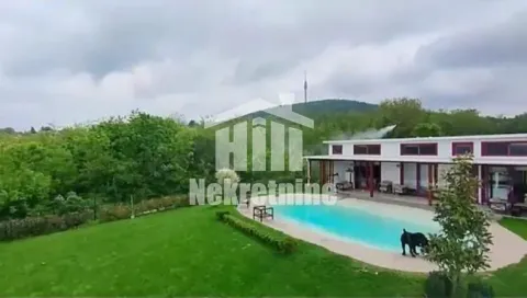 Pogled na dvorište kuće sa bazenom i zelenom površinom. - image 2