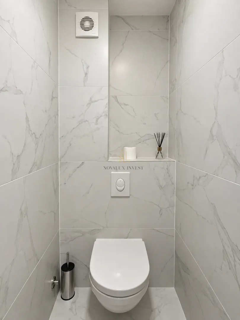 Small bathroom lined with marble tiles and a wall-hung toilet.