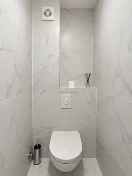 Small bathroom lined with marble tiles and a wall-hung toilet. - image 6