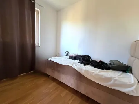 Manja spavaća soba sa krevetom, drvenim podom i prozorom sa zavjesom. - image 10