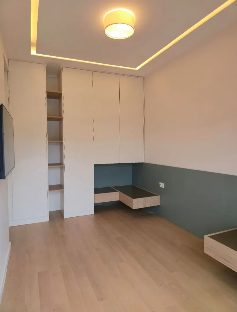 Moderna spavaća soba sa ugradnim plakarima i spuštenim plafonom sa rasvjetom.