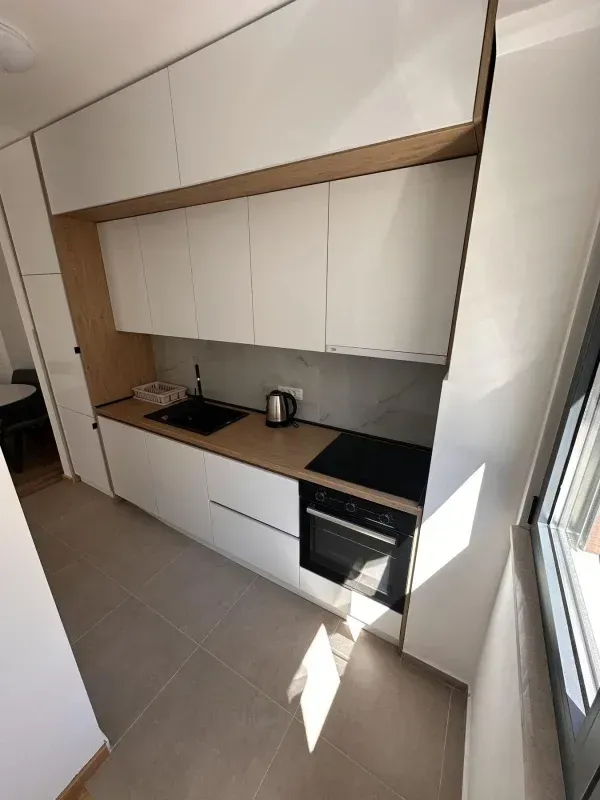 Moderna kuhinja sa bijelim elementima i drvenim detaljima.