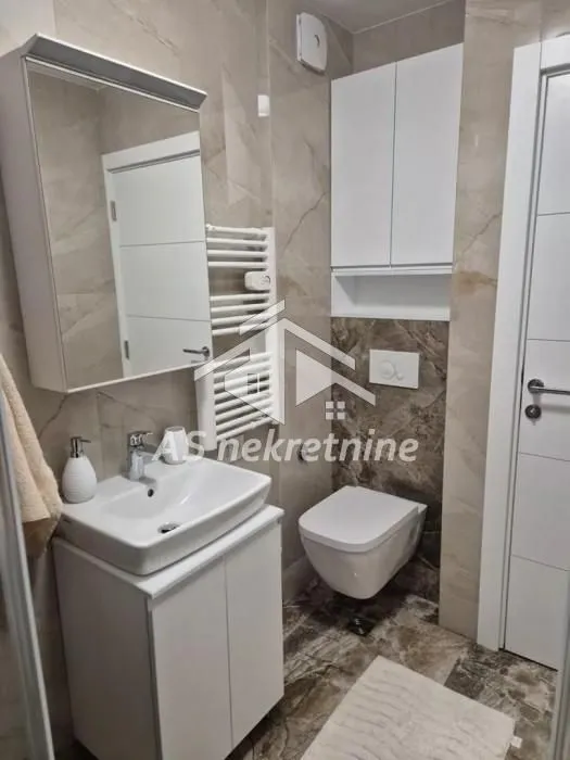 Modern bathroom with a washbasin, mirror, wall-hung toilet, and wall cabinet.