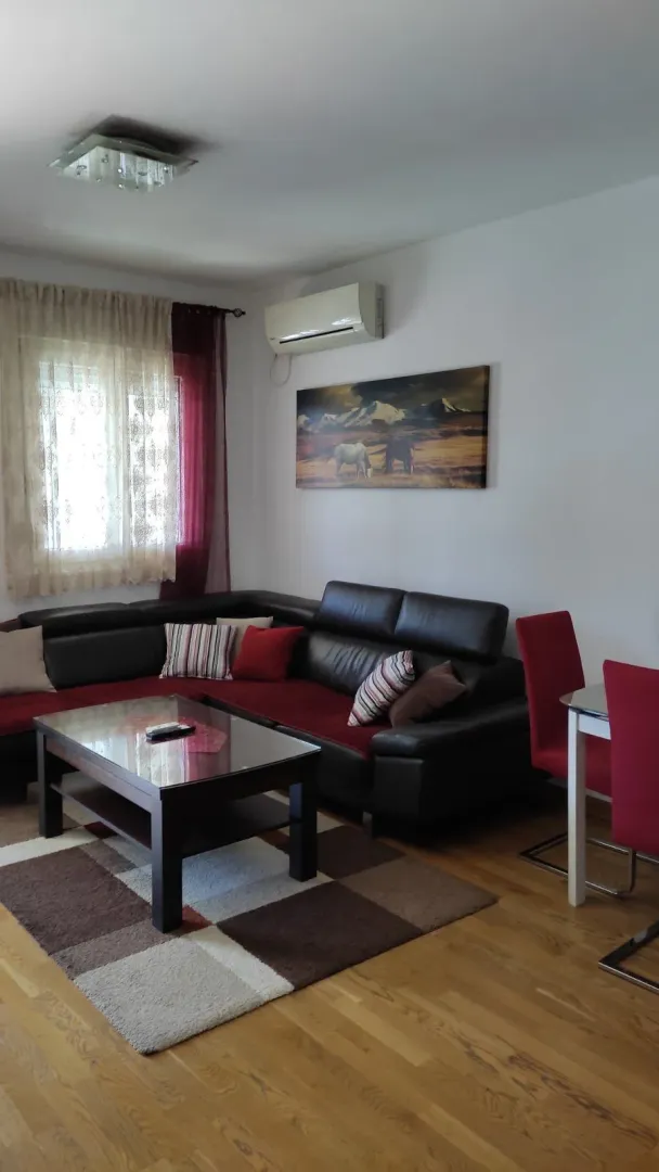 Living room with a corner sofa, coffee table, and a dining table with red chairs.