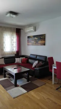 Living room with a corner sofa, coffee table, and a dining table with red chairs. - image 3