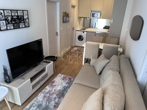 Living room with sofa, TV and kitchen in the background. - image 6