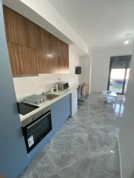 Moderna kuhinja sa bijelim radnim površinama, plavim donjim elementima i drvenim gornjim ormarićima u otvorenom prostoru. - image 2