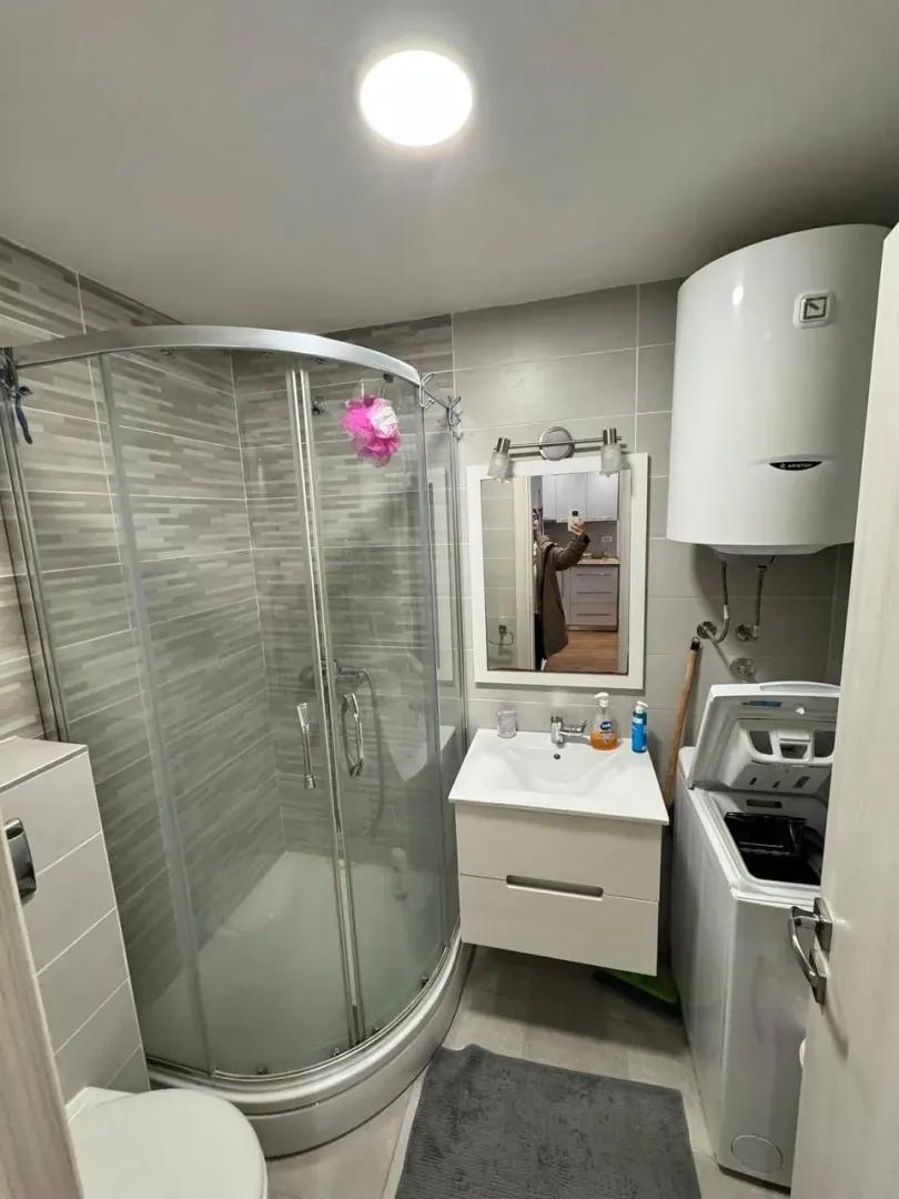 Small bathroom with a shower cabin, washbasin, and washing machine.
