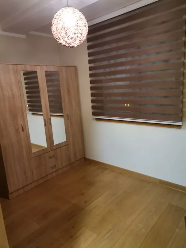 Small room with a wooden wardrobe, parquet flooring, and window blinds.