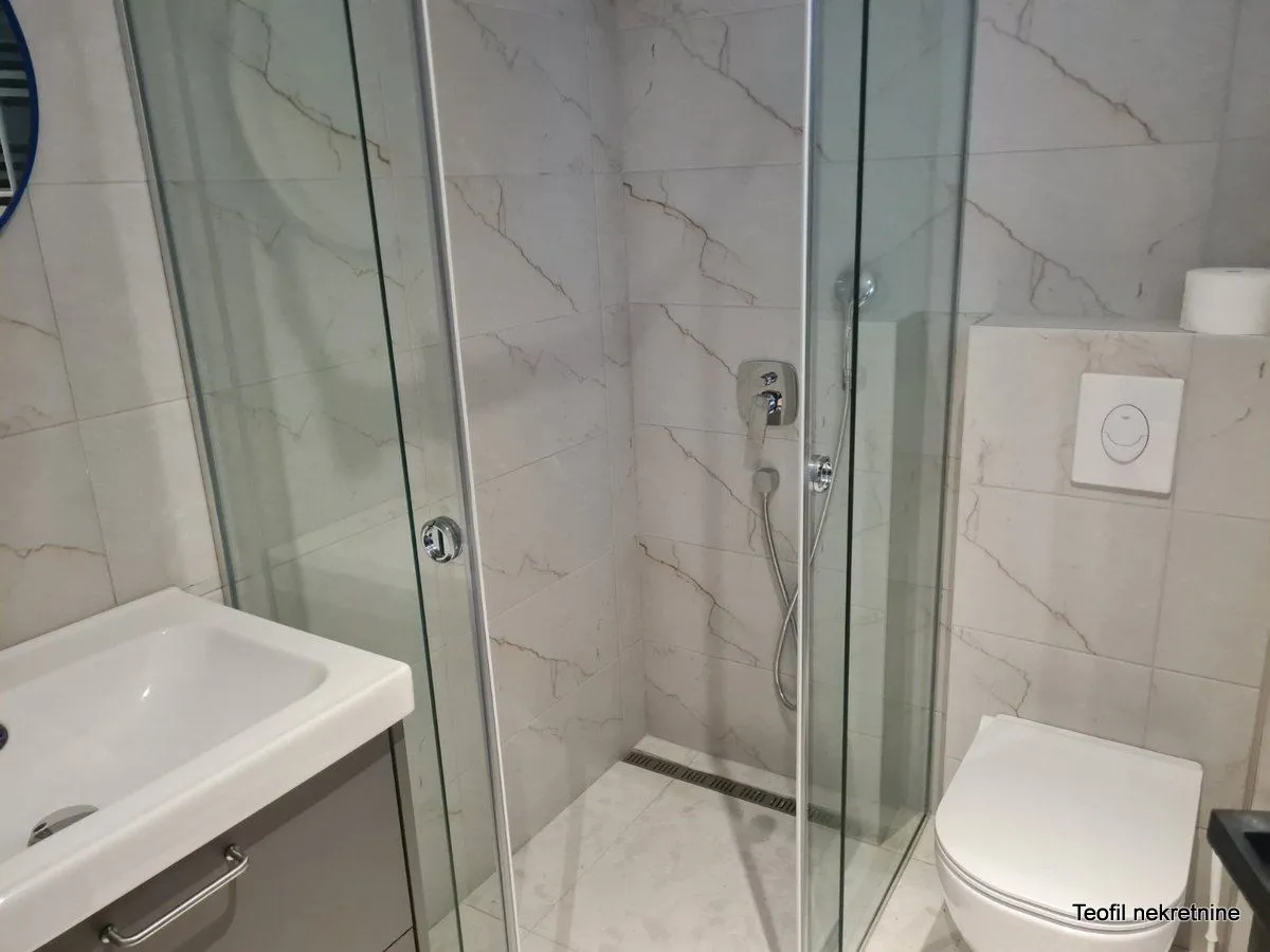 Bathroom with a shower cabin, washbasin, and wall-hung toilet.