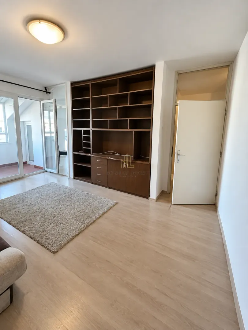 Living room with a large wooden bookshelf and access to the terrace.