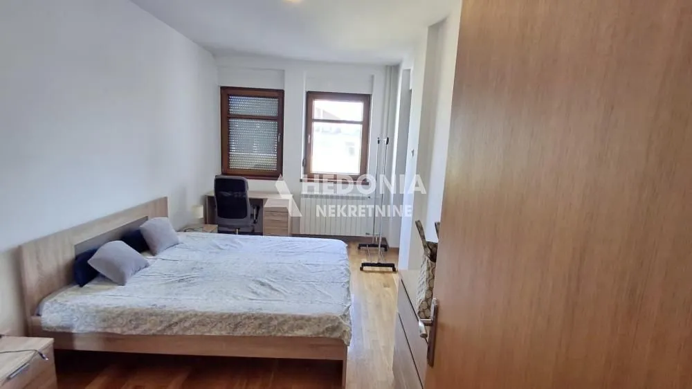 Furnished bedroom with a double bed, desk, and windows.