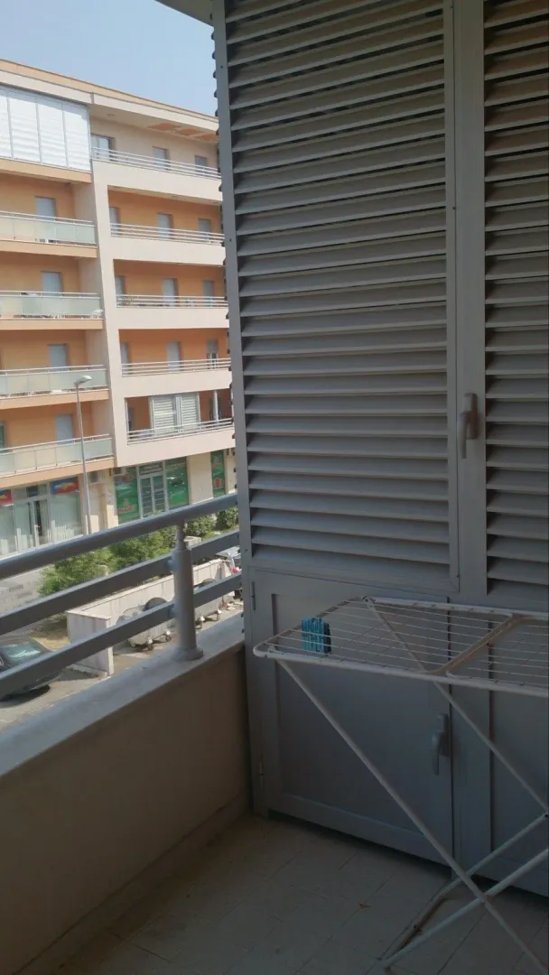A balcony with a clothes drying rack and a view of the neighboring building.