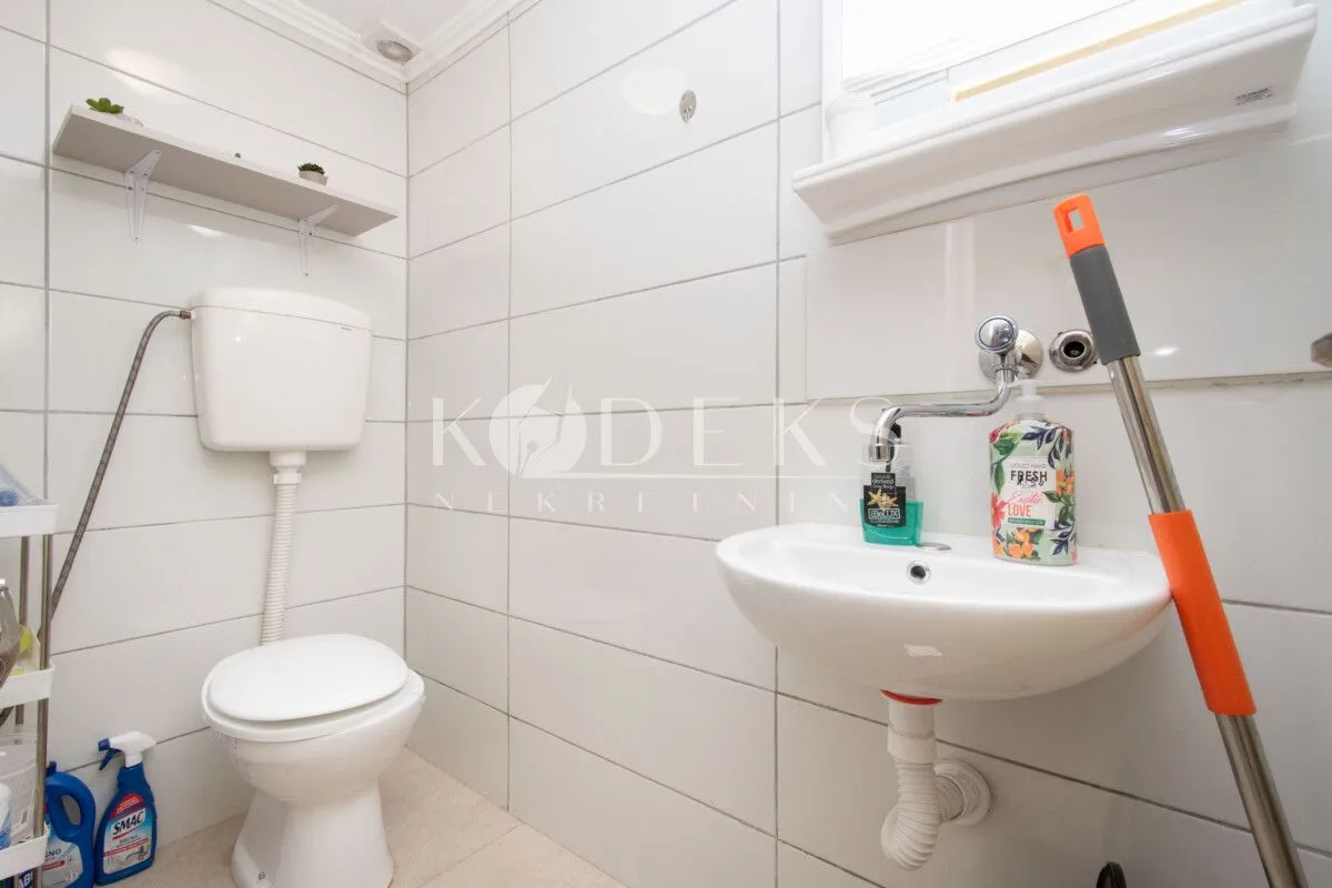 Bathroom equipped with a toilet bowl, washbasin, and white wall tiles.